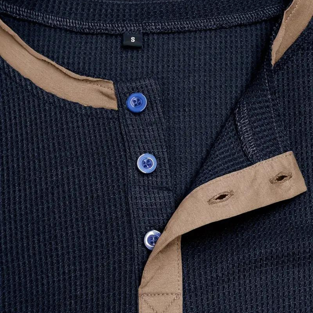 Dunkelblaues Herren-Henley-Shirt mit beigen Akzenten, Knopfleiste und blauen Knöpfen. Stilvolle Freizeitmode, ideal für Herbst und Winter.