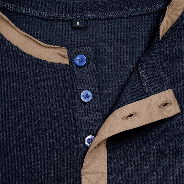 Dunkelblaues Herren-Henley-Shirt mit beigen Akzenten, Knopfleiste und blauen Knöpfen. Stilvolle Freizeitmode, ideal für Herbst und Winter.