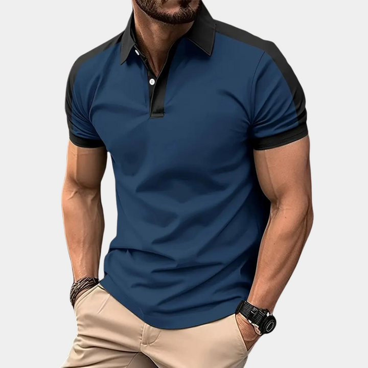 Mann in blauem Polohemd mit schwarzen Akzenten, muskulös, trägt beige Hose und Armbanduhr. Mode, Herrenbekleidung, sportlich-elegant.