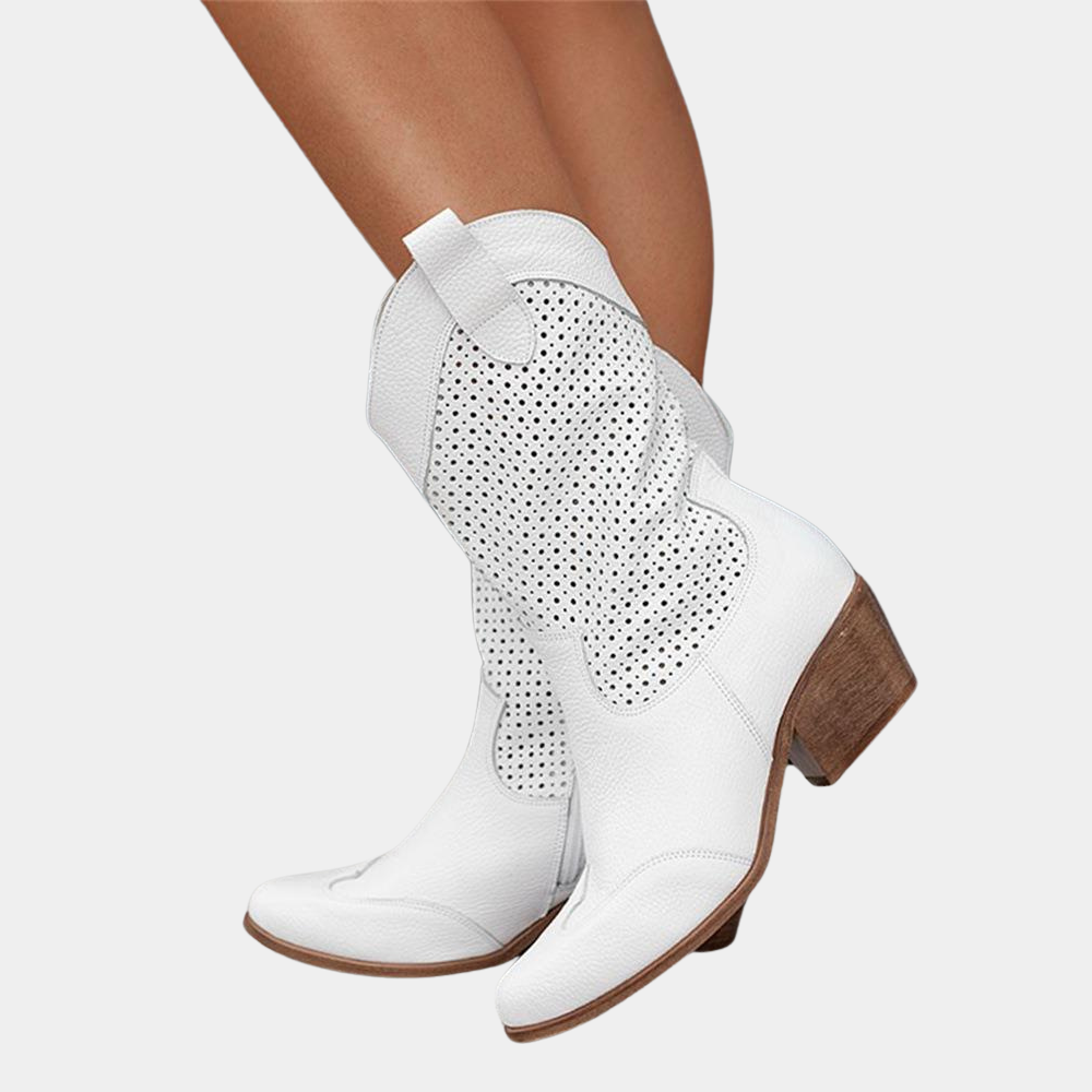 Weiße Cowboystiefel aus Leder mit perforiertem Muster und Holzabsatz, getragen an Beinen. Modische Damenstiefel, ideal für Western- und Sommerlooks.