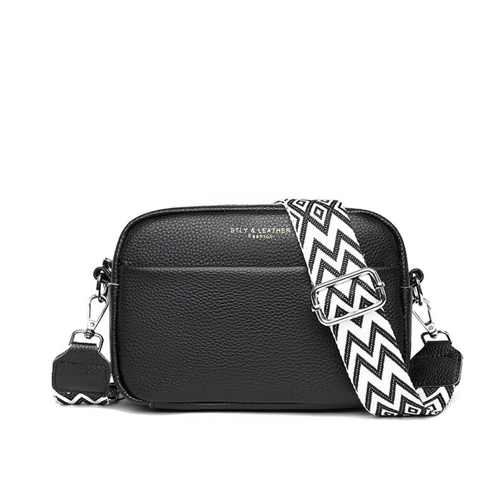 Schwarze Lederhandtasche mit Chevron-Muster Schulterriemen, silbernen Beschlägen und Fronttasche. Modische Damenaccessoire.
