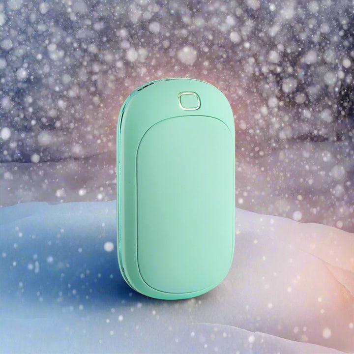 Türkisfarbener Handwärmer im Schnee, tragbares Heizgerät, ideal für Winter, Outdoor-Aktivitäten, wiederaufladbar, kompakt, ergonomisches Design.