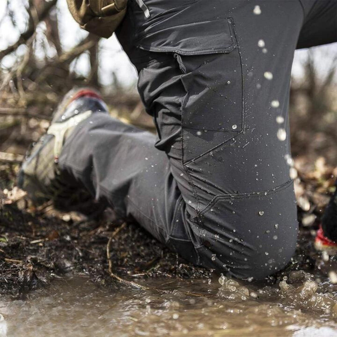Outdoor-Hose kniet im schlammigen Wasser, robustes Material, ideal für Wandern und Trekking, spritzwassergeschützt, Naturabenteuer.