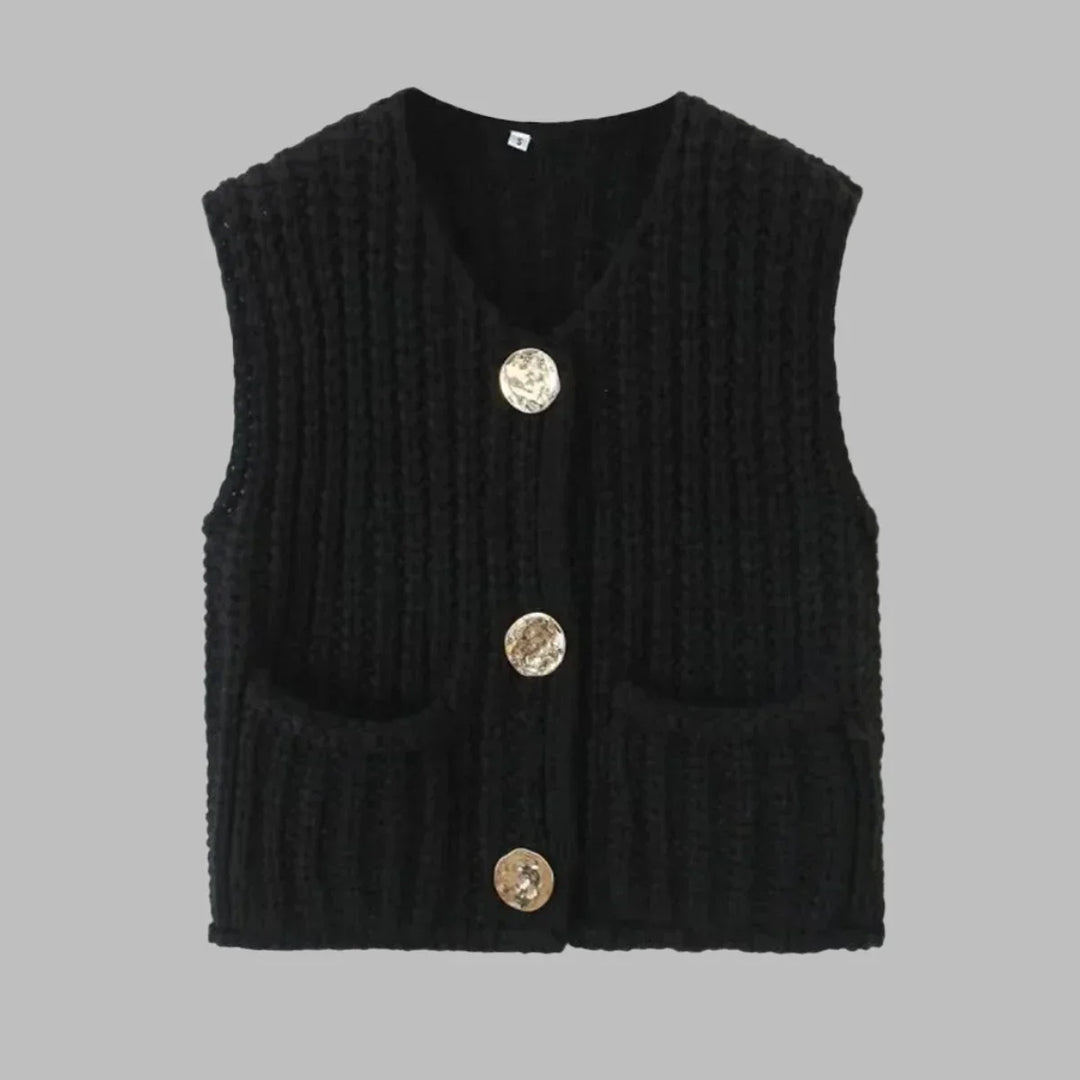 Schwarze Strickweste mit drei goldenen Knöpfen und zwei Taschen, ärmellos, auf grauem Hintergrund. Modische Damenbekleidung, Herbstmode.