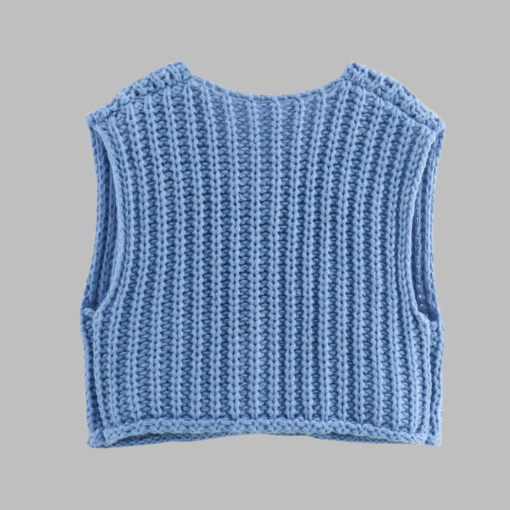 Blauer, handgestrickter Pullover ohne Ärmel auf grauem Hintergrund. Modischer Strickwesten-Trend, ideal für Herbst- und Wintermode.