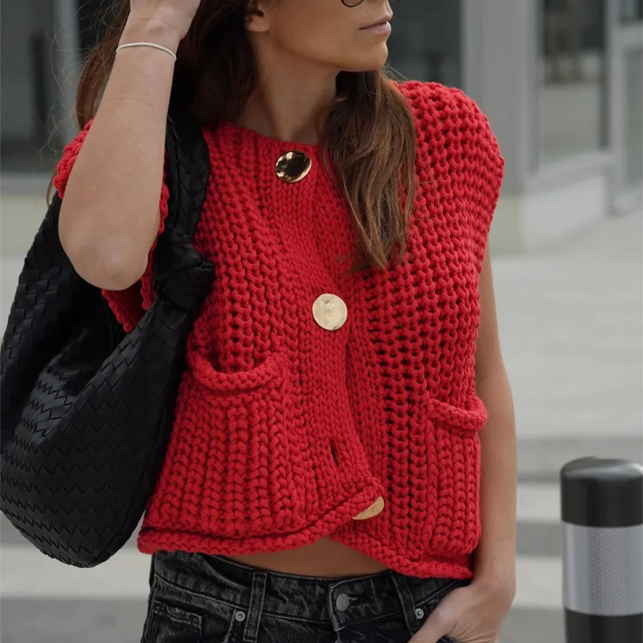 Frau trägt rote Strickweste mit großen Knöpfen, schwarze Tasche, Jeans. Modetrend Herbst, lässiger Streetstyle, urbaner Look.