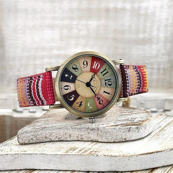 Vintage-Armbanduhr mit buntem Zifferblatt und gewebtem Stoffarmband, rustikaler Hintergrund. Retro-Uhr, modisches Accessoire, Unisex-Design.