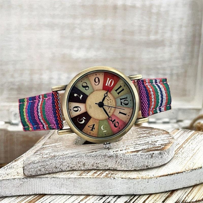 Bunte Armbanduhr mit gestreiftem Textilarmband, Vintage-Zifferblatt und großen Zahlen, auf rustikalem Holzuntergrund. Retro-Uhr, modisches Accessoire.
