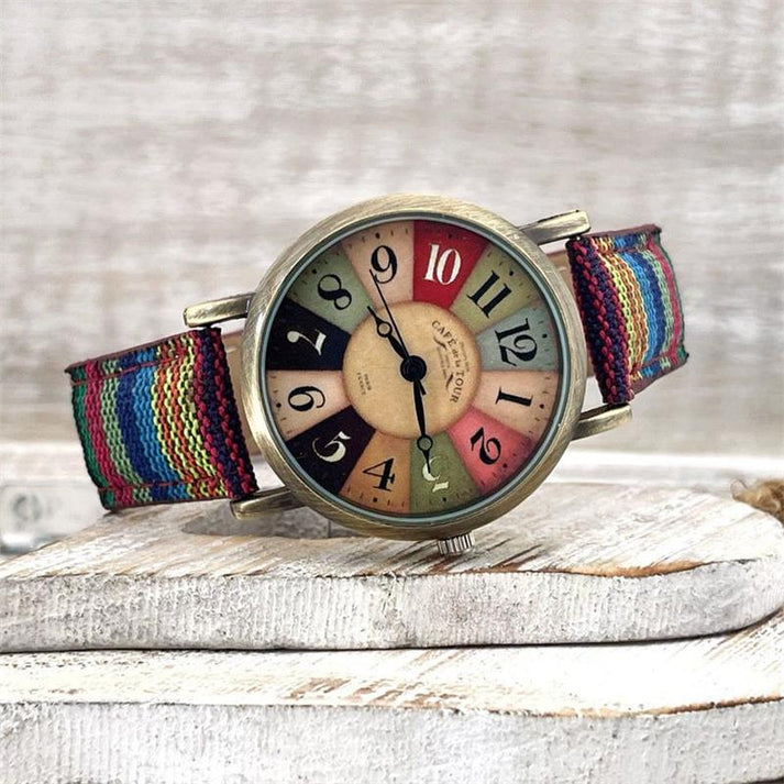 Bunte Armbanduhr mit mehrfarbigem Zifferblatt und gestreiftem Stoffarmband auf Holzuntergrund. Vintage-Stil, modisches Accessoire, Unisex-Uhr.