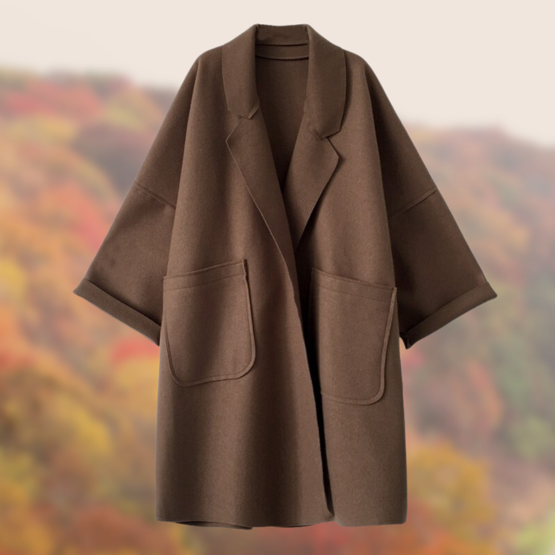 Brauner Wollmantel mit großen Taschen und weitem Schnitt vor herbstlichem Hintergrund. Eleganter Damenmantel, ideal für kühle Herbsttage.