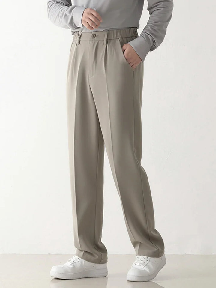 Graue Herrenhose mit elastischem Bund, getragen von einer Person in grauem Pullover und weißen Sneakers. Bequeme, stilvolle Herrenmode.
