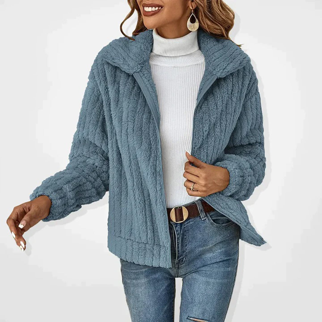 Frau in blauer Plüschjacke, weißem Rollkragenpullover und Jeans. Modetrend Herbst/Winter, stilvolle Damenbekleidung, gemütlicher Look.