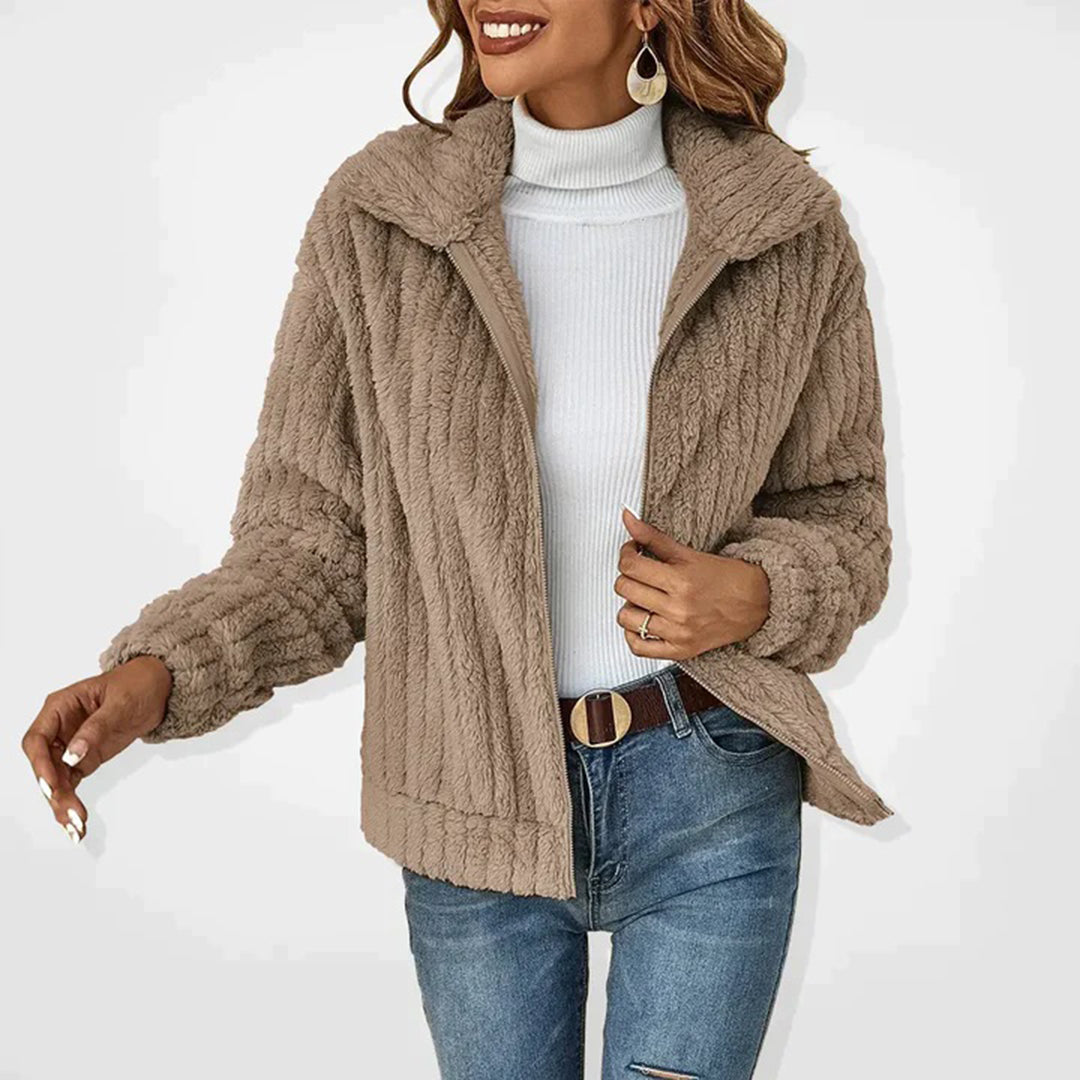 Frau in beiger Teddyfelljacke, weißem Rollkragenpullover und blauen Jeans. Modetrend Herbst/Winter, stilvolle Damenbekleidung, warme Jacke.