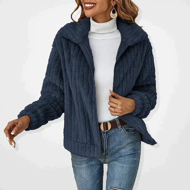 Dame in blauer Strickjacke, weißem Rollkragenpullover und Jeans. Modetrend Herbst/Winter, stilvolle Damenbekleidung, gemütlicher Look.