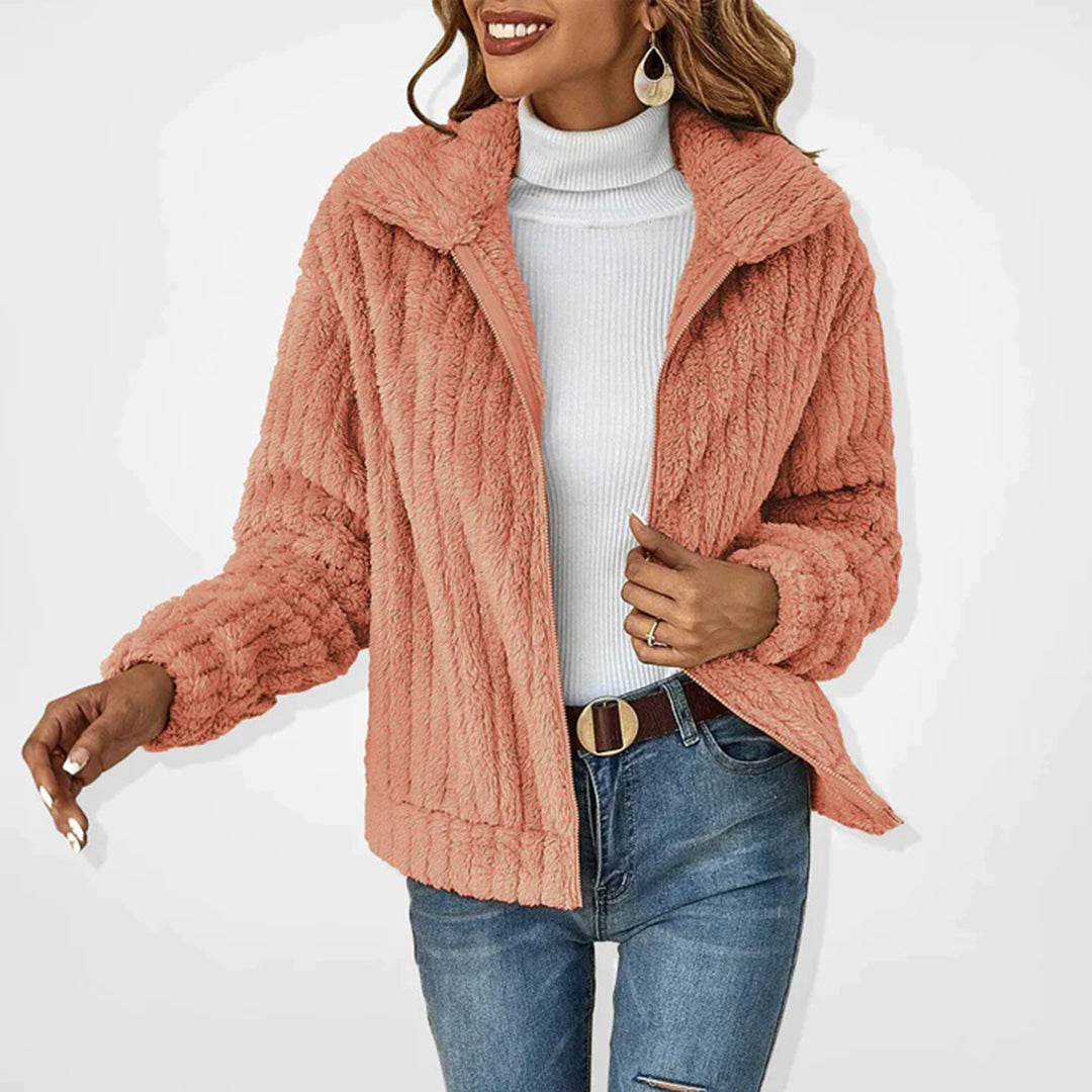 Frau trägt flauschige rosa Teddyjacke, weißen Rollkragenpullover und blaue Jeans. Modetrend Herbst/Winter, stilvolle Damenbekleidung.