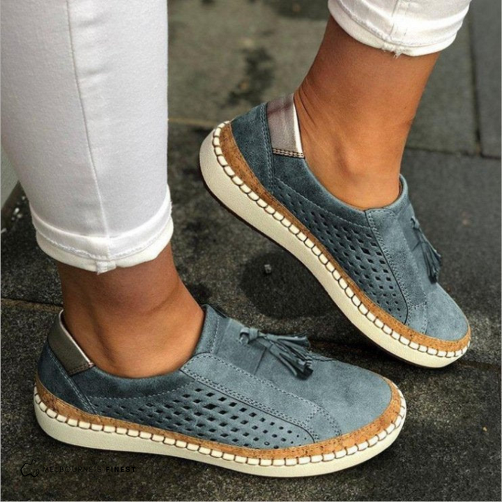 Damen-Sneaker in Blau mit Lochmuster und Quasten, kombiniert mit weißen Hosen. Bequeme Freizeitschuhe für den Alltag.