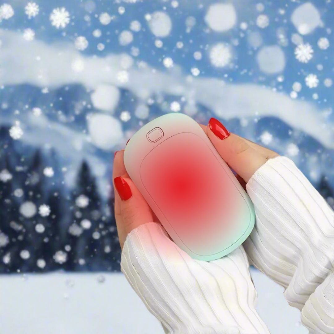 Hände mit roten Nägeln halten einen elektrischen Handwärmer im Schnee. Winter, tragbarer Handwärmer, kalte Jahreszeit, Schneefall.
