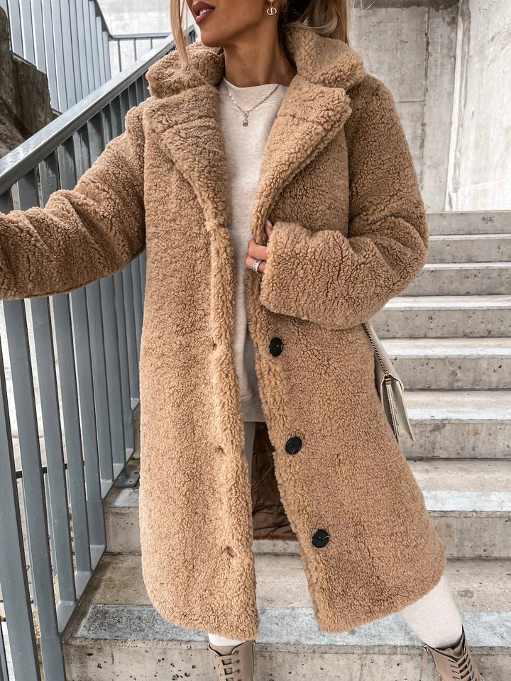 Frau in beigem Teddy-Mantel auf Treppe, modischer Winterlook, kuscheliger Wollmantel, Streetstyle, warme Damenbekleidung, trendige Herbstmode.