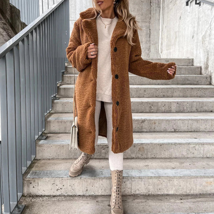 Frau in braunem Teddy-Mantel und beigen Stiefeln auf Treppe. Modischer Winterlook, urbaner Stil, gemütliche Kleidung, Outdoor-Fashion.