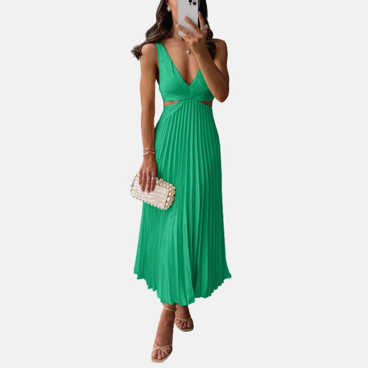 Frau in elegantem, grünem Abendkleid mit V-Ausschnitt und Plisseefalten, hält eine Perlen-Clutch, trägt Sandaletten. Perfekt für Sommermode.