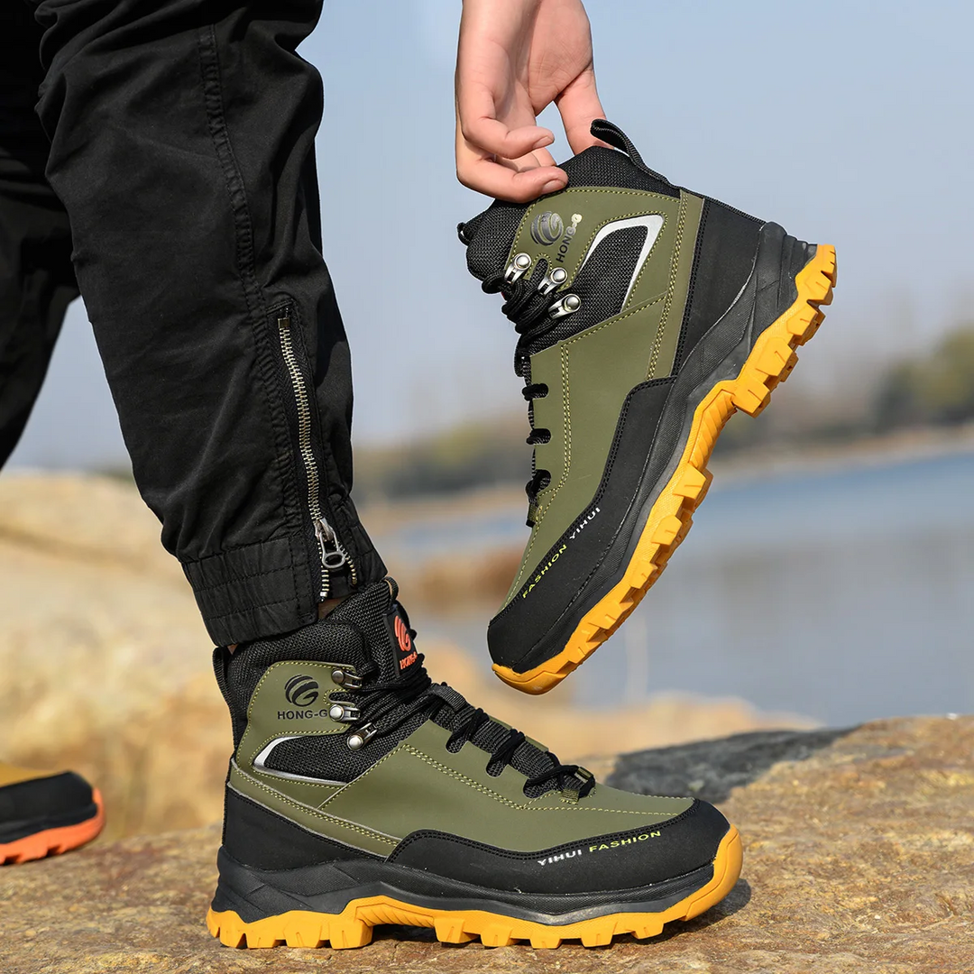 Person trägt grüne Outdoor-Wanderschuhe mit gelber Sohle auf Felsen. Robuste Trekkingstiefel, ideal für Bergwanderungen und Outdoor-Aktivitäten.