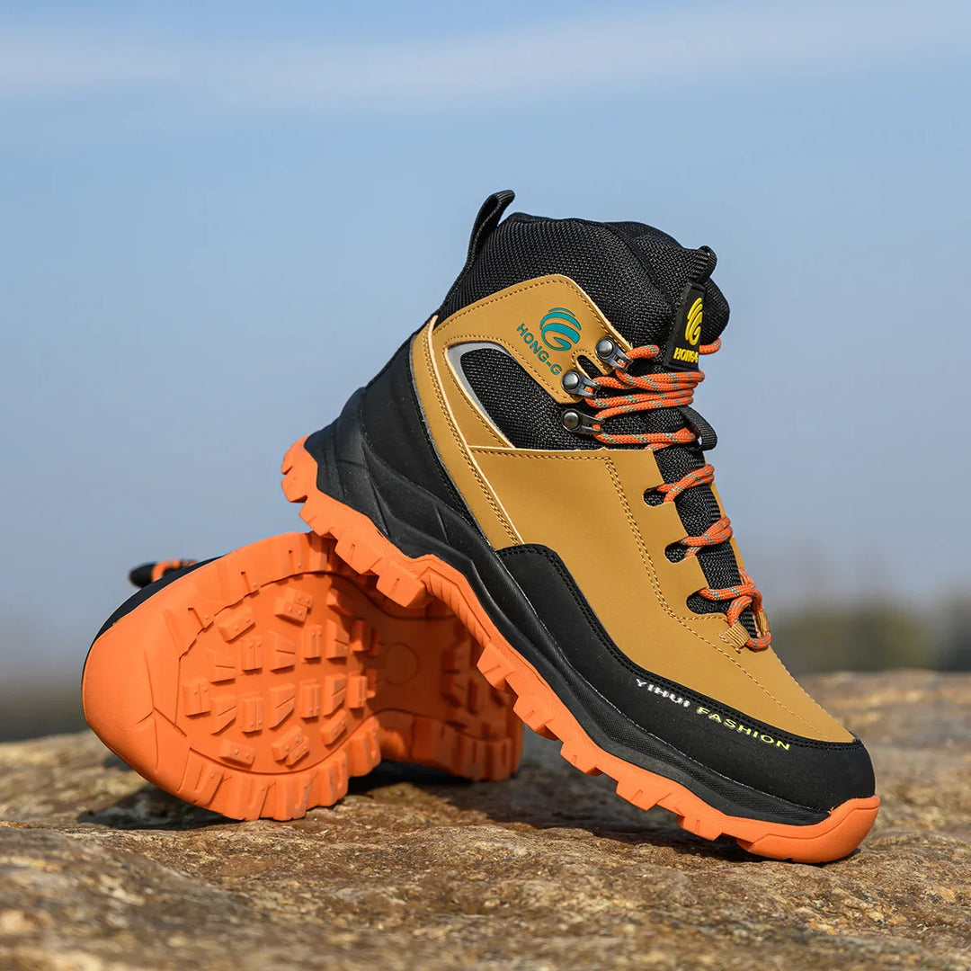 Braune und schwarze Wanderschuhe mit orangefarbener Sohle auf Felsen, robustes Design, ideal für Outdoor-Aktivitäten und Trekking.