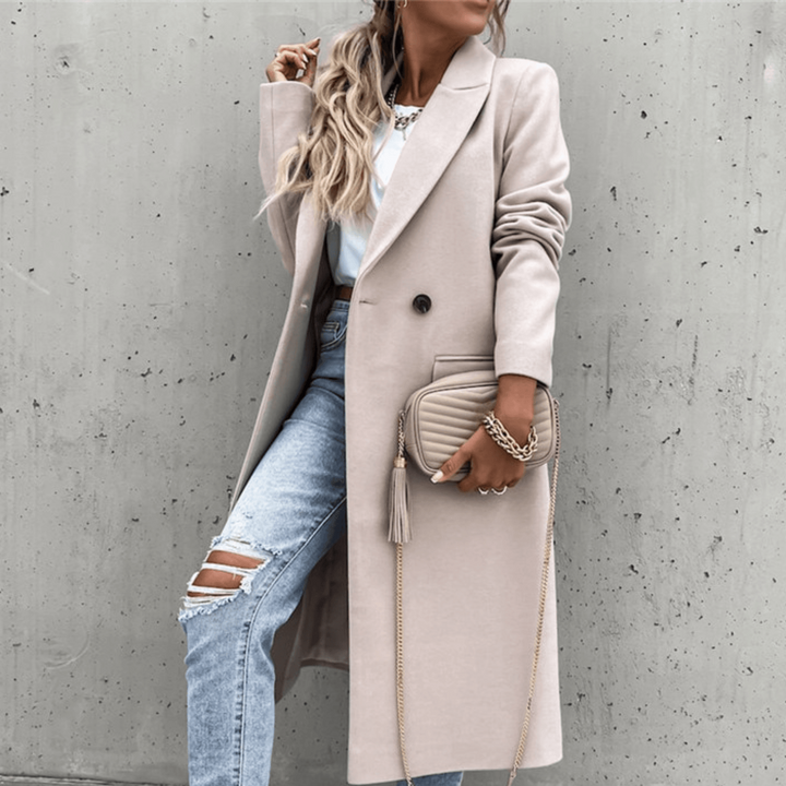 Elegante Frau in beigem Mantel, zerrissene Jeans, weiße Sneakers, hält eine beige Umhängetasche. Modetrend, Streetstyle, Herbstmode.