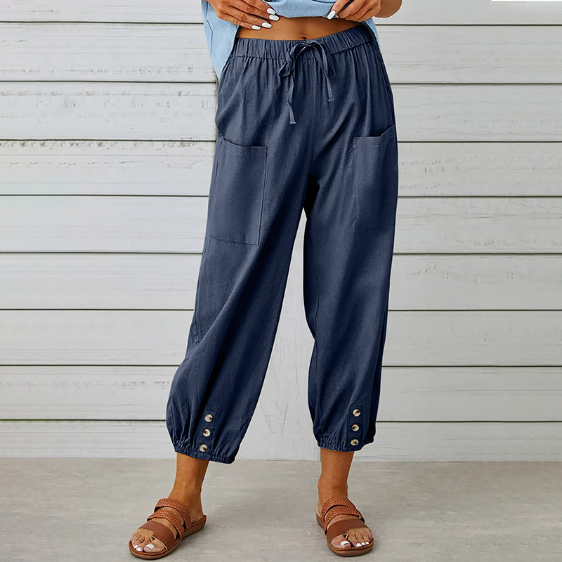 Damenhose aus Leinen in Dunkelblau mit elastischem Bund und Knöpfen am Saum, kombiniert mit Sandalen. Ideal für Sommermode und Freizeitkleidung.