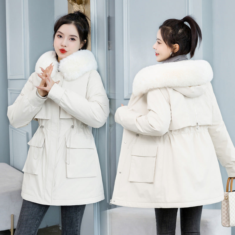 Frau in weißem Wintermantel mit Fellkragen vor Spiegel. Modetrend, Wintermode, Damenjacke, stilvoll, warm, elegant, modisch, Outdoor-Bekleidung.