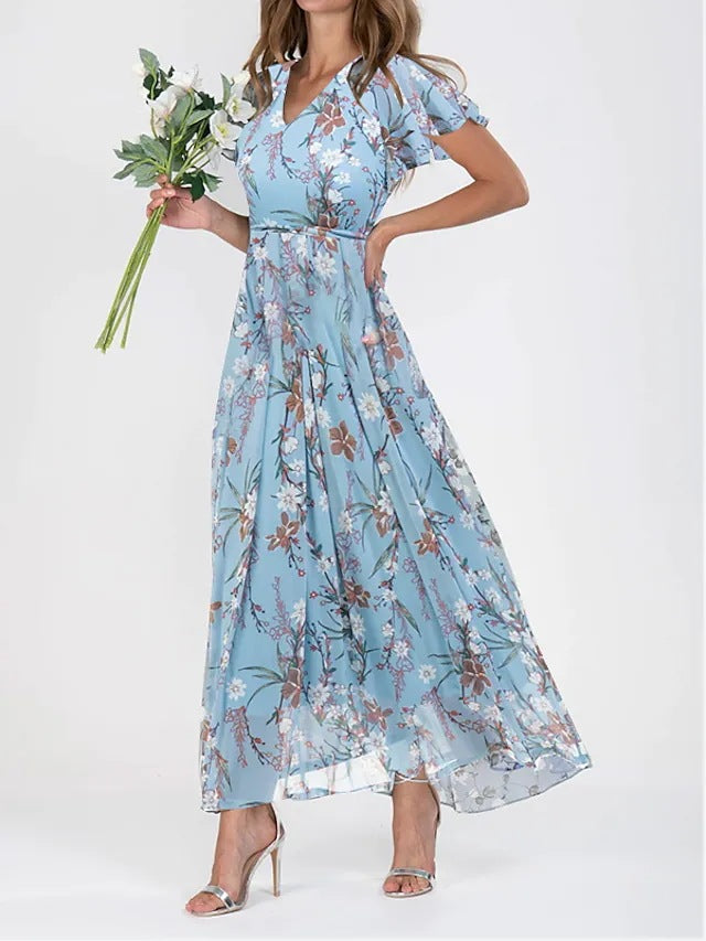 Frau in langem, blumigem, blauem Kleid mit Blumenstrauß, elegante Mode, Sommerkleid, florales Design, stilvolle Damenbekleidung.