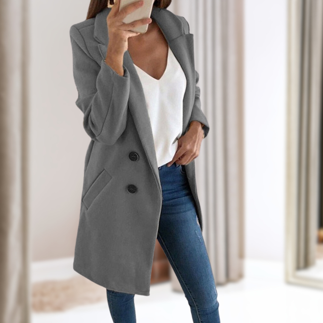 Dame im grauen Mantel, weißem Top und blauer Jeans macht Selfie im Spiegel. Modetrend, Herbstmode, stilvolle Damenbekleidung, eleganter Look.
