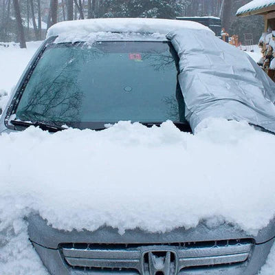 Auto mit Schneedecke und halb abgedeckter Windschutzscheibe im Winter. Schneeschutz, vereiste Autoscheibe, Winterwetter, Fahrzeugpflege.