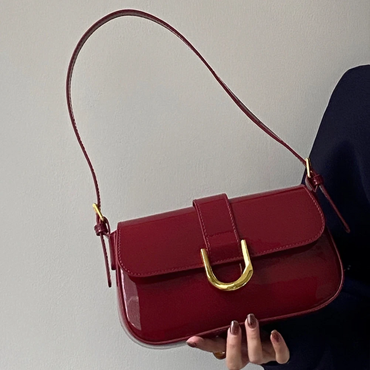 Rote Lederhandtasche mit goldener Schnalle, elegantes Design, Damenmode-Accessoire, glänzende Oberfläche, stilvoller Look, Trend 2023.