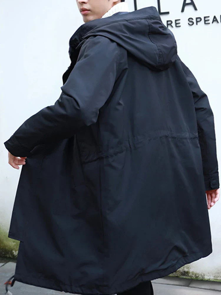 Mann in schwarzem, langem Parka mit Kapuze, seitlich fotografiert. Winterjacke, Outdoor-Bekleidung, modisch, wetterfest.