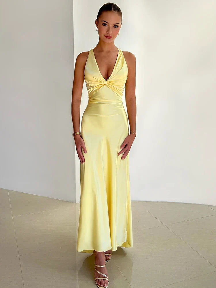 Frau in elegantem, gelbem Abendkleid mit V-Ausschnitt, posiert vor weißer Wand. Perfekt für Mode, Abendmode, Damenkleider, stilvolle Outfits.