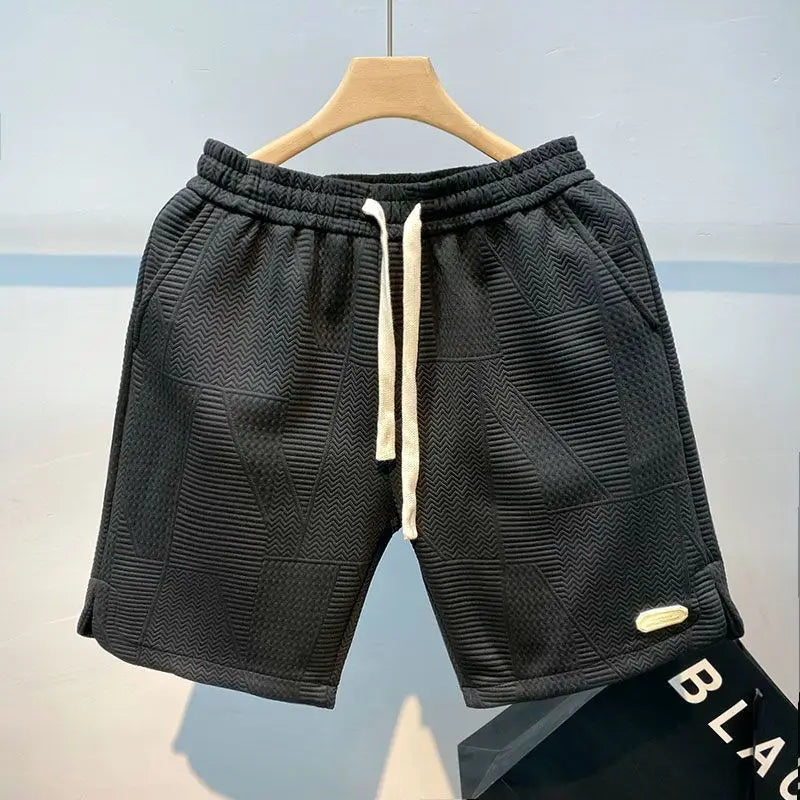 Schwarze Herren-Shorts mit Kordelzug, geometrischem Muster und elastischem Bund, auf einem Kleiderbügel präsentiert. Ideal für Freizeit und Sport.