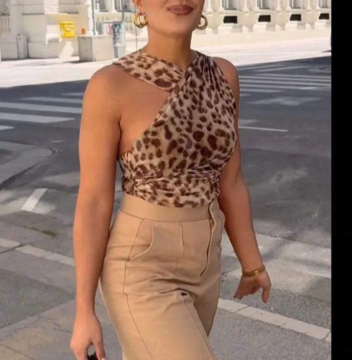 Frau in eleganter, ärmelloser Leoparden-Top und beigen Hose spaziert in städtischer Umgebung. Modetrend, Sommeroutfit, Streetstyle.