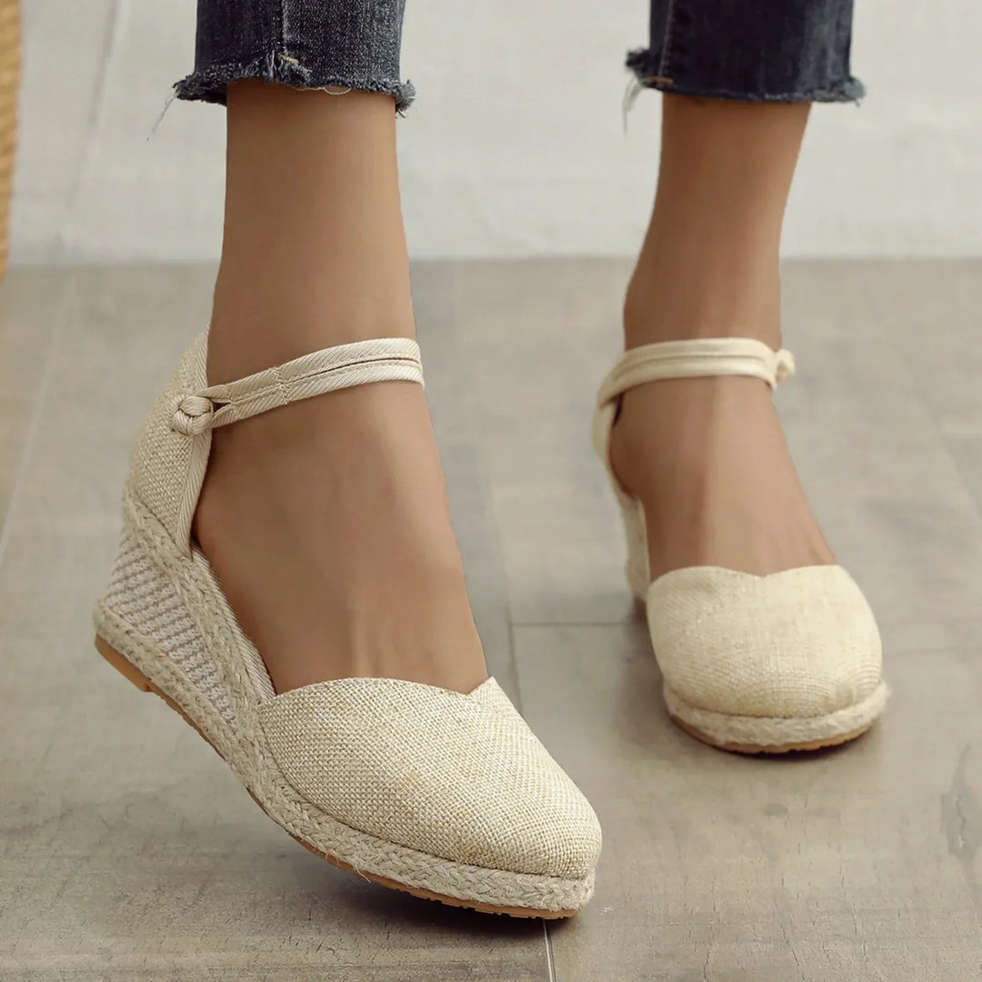 Damen Espadrilles Keilsandalen aus Leinen, beige, mit Knöchelriemen, auf Holzfußboden. Modische Sommerschuhe, ideal für Freizeit und Strand.