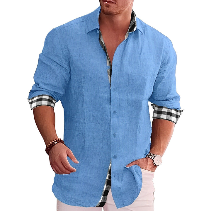Mann in hellblauem Leinenhemd mit karierten Manschetten, lässig gekleidet, trägt Armband und Uhr. Mode für Herren, Freizeitlook, stilvolles Outfit.