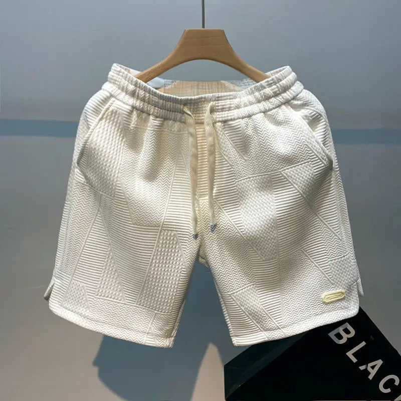 Weiße Herren-Shorts mit geometrischem Muster, aus Baumwolle, auf Holzkleiderbügel. Moderne Freizeitmode, ideal für Sommer und Sport.
