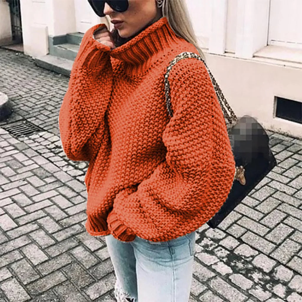 Frau in orangefarbenem Strickpullover, Jeans und Sonnenbrille auf Kopfsteinpflasterstraße. Modetrend, Herbstmode, lässiger Stil.