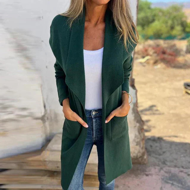 Frau in grünem Cardigan, weißem Top und blauer Jeans im Freien. Modischer Herbst-Look, lässiger Stil, Damenmode, Outdoor-Hintergrund.