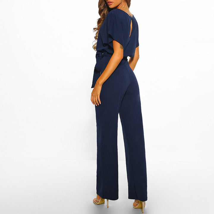Frau in eleganter, dunkelblauer Jumpsuit mit Gürtel, Rückansicht. Modetrend, Damenbekleidung, stilvolle Abendmode, schicke Einteiler.