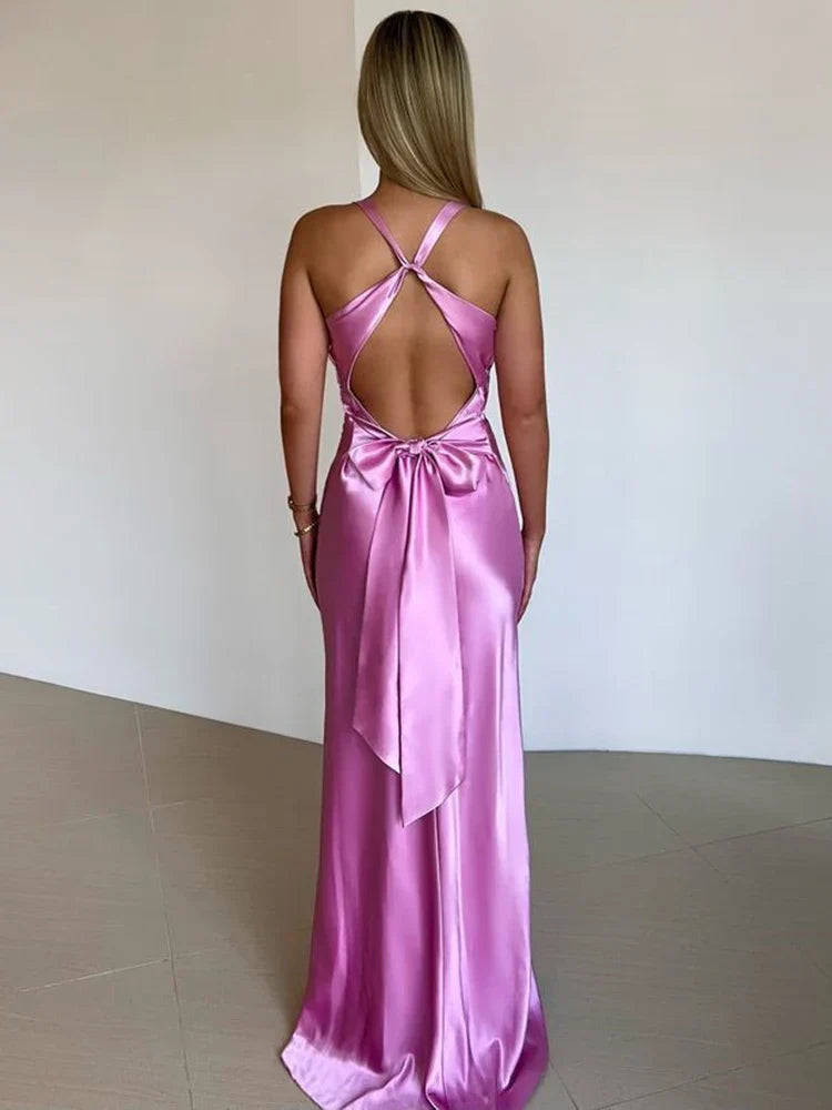 Frau in langem, rosa Satin-Abendkleid mit offenem Rücken und Schleife, elegantes Design, modisches Abendoutfit, stilvolle Abendmode.