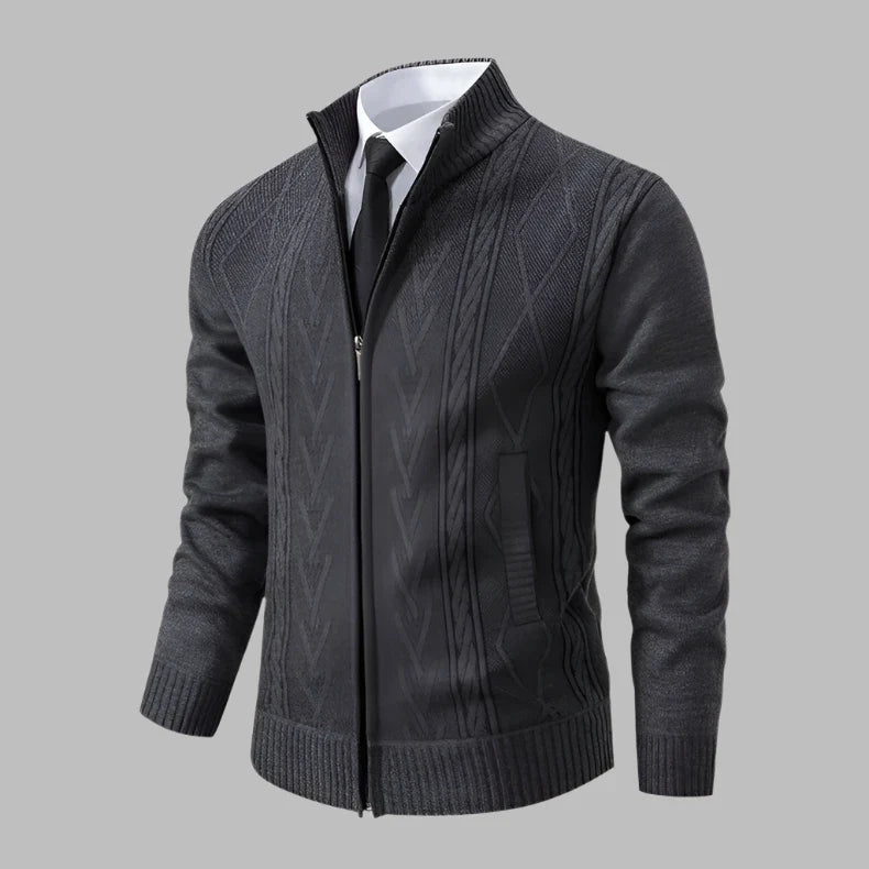 Dunkelgrauer Herren-Strickjacke mit Reißverschluss, elegantem Zopfmuster, kombiniert mit weißem Hemd und schwarzer Krawatte, auf grauem Hintergrund.