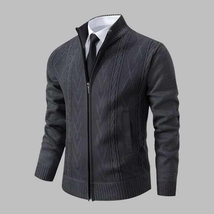 Dunkelgrauer Herren-Strickjacke mit Reißverschluss, elegantem Zopfmuster, kombiniert mit weißem Hemd und schwarzer Krawatte, auf grauem Hintergrund.