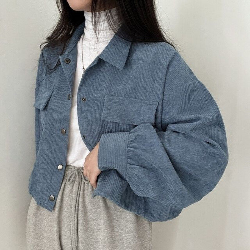 Frau trägt blaue Cordjacke über weißem Rollkragenpullover, kombiniert mit grauer Jogginghose. Modetrend, lässiger Stil, Herbstmode.