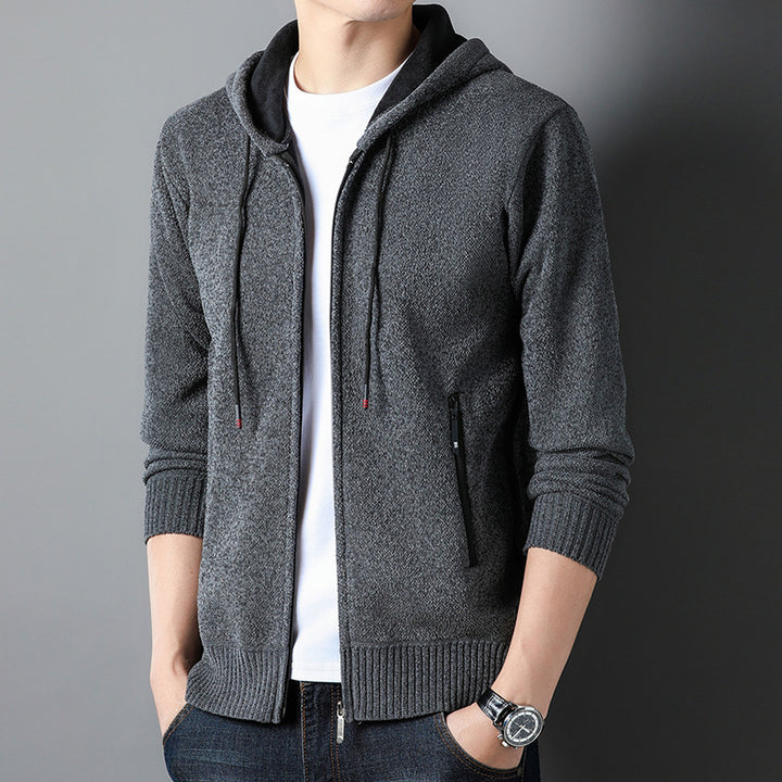 Grauer Herren-Hoodie mit Reißverschluss, Kapuze und Kordelzug, kombiniert mit weißem T-Shirt und Jeans. Modische Freizeitkleidung für Männer.