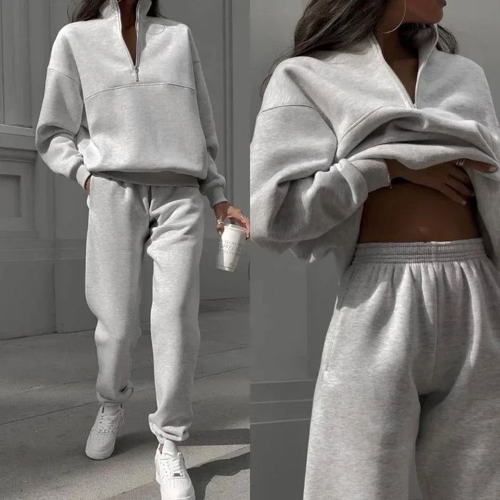 Graues Damen-Sweatshirt und Jogginghose Set, sportlich und bequem, ideal für Freizeit und Fitness. Perfekt kombiniert mit weißen Sneakers.
