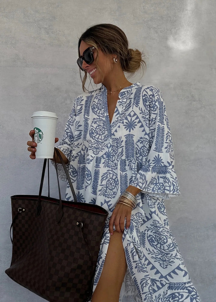 Frau in weiß-blauem Sommerkleid mit Sonnenbrille hält Starbucks-Becher und braune Designer-Handtasche. Elegante Mode, Sommerstil, Accessoires.
